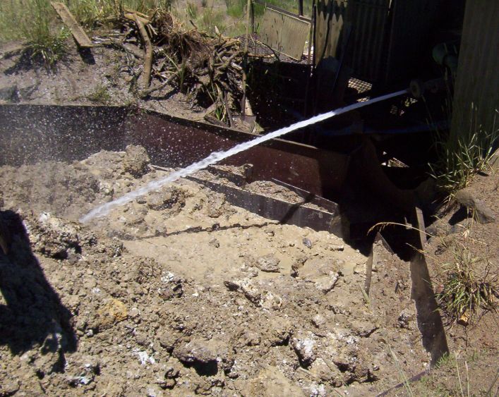 High pressure jet of water breaking up trubloads of wash before entering the trommel